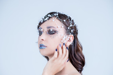 Beautiful model girl with blue manicure nail design,face and hair with beads, rhinestones ,decoration. Fashion makeup and care for hands and nails and cosmetics.Nail art design.emale beauty. Luxury