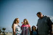 © Cavan Images - Happy family standing at beach against sky during sunny day