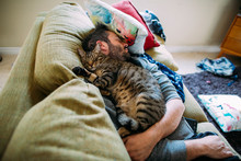 High Angle View Of Man With Cat Sleeping On Sofa At Home