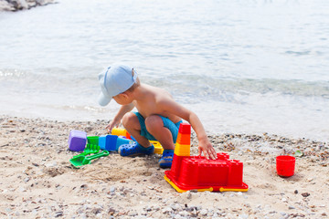 Small child is playing with sand on the beach