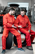 © rh2010 - Car service workers in red uniform having a break sitting together on the wheels at the tire mounting service
