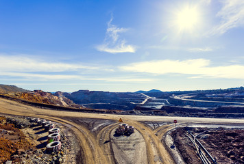 Aerial view of opencast mining quarry with sun and blue sky