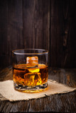 Fototapeta Tulipany - Whiskey with ice cube in a glasses on a rustic dark wooden table