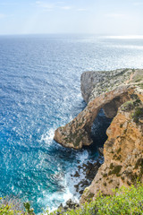 Famous natural limestone arch of the Blue Grotto is a number of sea caverns on the south coast of Malta. The water mirroring showing numerous shades of blue and phosphorescent colours of the flora Blu