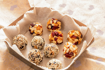 Two kinds of handmade energy balls are lying in cardboard box on wrapping paper.