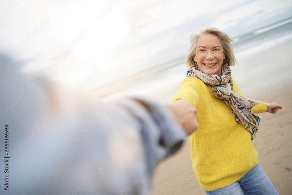 Energetic senior woman holding hands with husband in playful manner - obrazy, fototapety, plakaty 