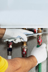 Wall Mural - A plumber attaches to a gas pipe boiler with a wrench