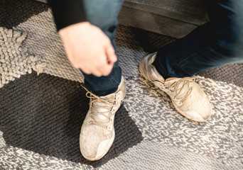 close up man put on casual sneakers and tie shoelaces on the couch and carpet b