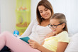 © Syda Productions - people, family and education concept - happy daughter with mother reading book at home