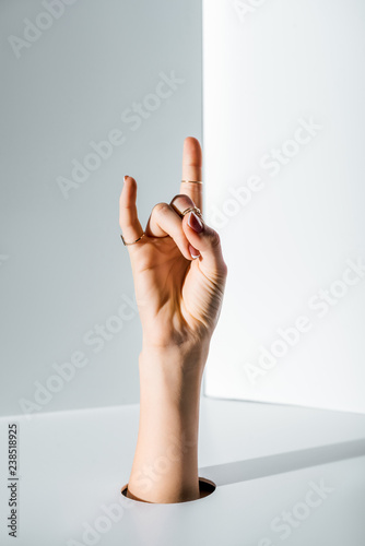 Fotografie, Obraz cropped image of woman showing rock sign through hole on white