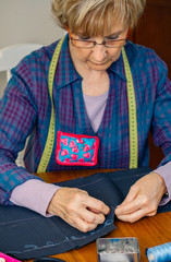 Wall Mural - Senior female seamstress sewing cloth to make a garment in her workshop