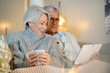 © goodluz - Senior couple relaxing at home on couch with tablet