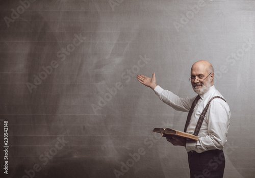 Fotomural Smiling confident professor teaching and pointing at the blackboard
