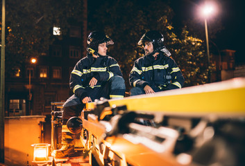 Wall Mural - Two Fireman Man pose on top of a truck.