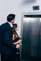 Wall Mural - couple in formal wear holding champagne glasses and waiting for elevator