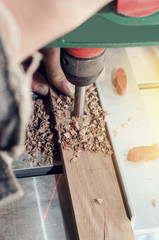 Wall Mural - Drill a mill for a tree in the boring machine with a laser marking. Hands master drills a hole in a wooden bar.