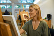 © Westend61 - Smiling student painting on easel in art class