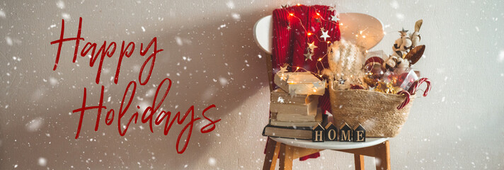 Winter sweater laid on a chair with a basket of Christmas decorations, books. Holiday decoration with the inscription HOME. 