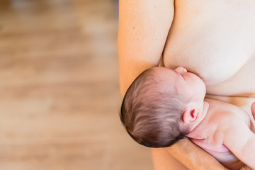 Newborn baby sucking breastfeeding from his mother's breast.