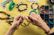 Jewelry Making. Female Hands With A Tool On A Yellow Background..