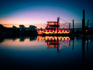 Boat in a harbor decorated with colorful christmas lights 