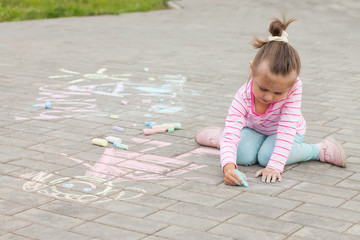 little girl draws a chalk