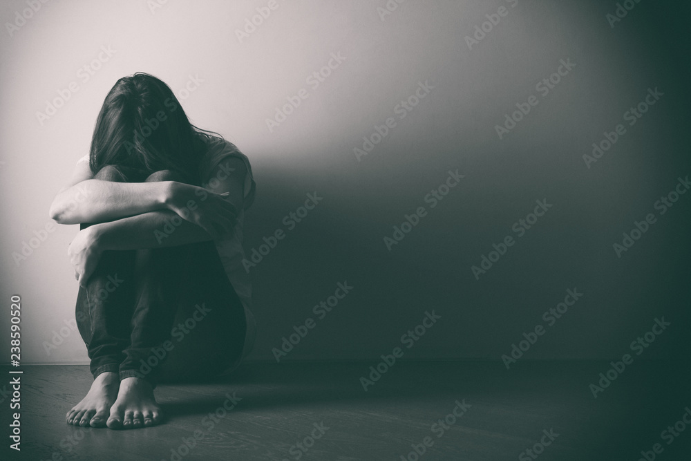 Teenager girl with depression sitting alone on the floor in the dark room. . Black and white photo - obrazy, fototapety, plakaty 