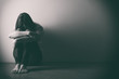 Leinwandbild Motiv Teenager girl with depression sitting alone on the floor in the dark room. . Black and white photo