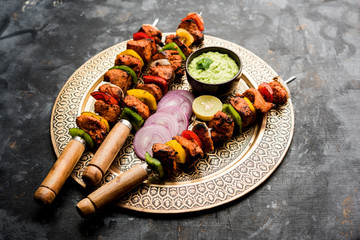 Wall Mural - Chicken tikka /skew Kebab. Traditional Indian dish cooked on charcoal and flame, seasoned & colourfully garnished. served with green chutney and salad. selective focus