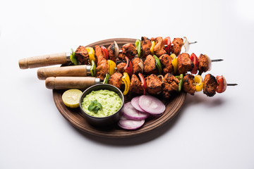 Wall Mural - Chicken tikka /skew Kebab. Traditional Indian dish cooked on charcoal and flame, seasoned & colourfully garnished. served with green chutney and salad. selective focus