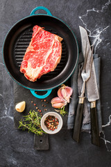 Wall Mural - Raw Fresh Marbled Meat Beef Steak rosemary, spices on the grill pan. Black marble background. Top View Copy space for Text