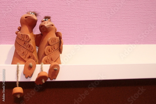 Fotografie, Obraz Two embracing funny birds sitting on a shelf - ceramic statuette on white pink b