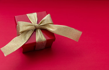 Wall Mural - red gift box with gold ribbon on red background, view from above, copy space