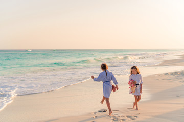 Little girls having fun at tropical beach playing together at shallow water.