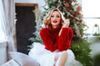 © Margo Basarab - holidays, celebration and people concept - smiling woman in red sweater over christmas tree background