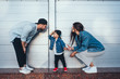 © teksomolika - Young family is having fun on the street near the wall