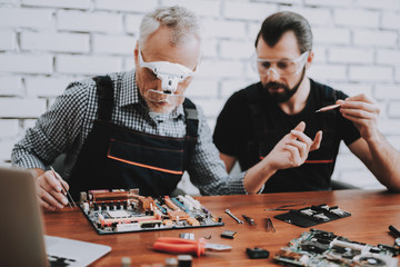 Two Men Repairing Hardware Equipment in Workshop.