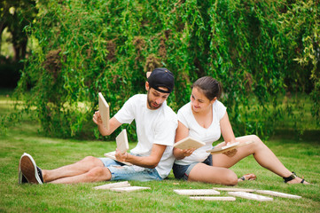 Wall Mural - Young man and woman playing giant dominoes in the Park on the grass.