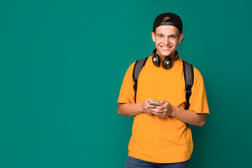 Teen guy texting on smartphone over turquoise background