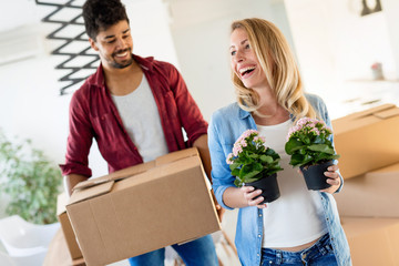 Wall Mural - Young couple unpacking cardboard boxes at new home moving in concept