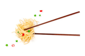 An overhead photo of chopsticks with udon noodles in a nest shape, green peas and red peppers, shot from the top on a white background with copy space. Spicy Asian food