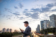 © Blue Jean Images - Side view of young businessman using smartphone outdoors
