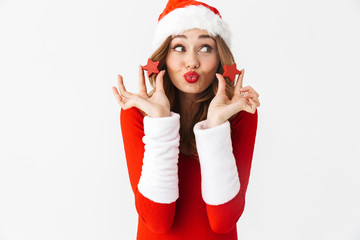 Poster - Portrait of joyful woman 20s wearing Santa Claus red costume smiling and holding Christmas decorations, isolated over white background