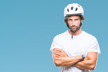 Wall Mural - Handsome hispanic cyclist man wearing safety helmet over isolated background skeptic and nervous, disapproving expression on face with crossed arms. Negative person.