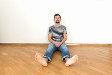 A Young Man Is Sitting On The Floor In A New Apartment.