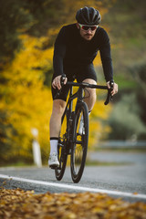 Wall Mural - Professional road bicycle racer in action. Men cycling mountain road bike at sunset.