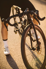 Wall Mural - Professional road bicycle racer posing. Men cycling mountain road bike at sunset.