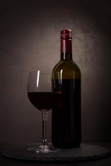 Wall Mural - Wine bottle and glass with red wine on dark wooden background. Celebration concept. Copy space