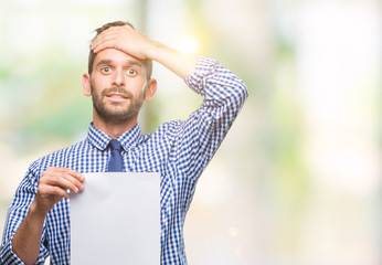 Young handsome man holding blank paper over isolated background stressed with hand on head, shocked with shame and surprise face, angry and frustrated. Fear and upset for mistake.