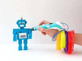 A child, teen boy makes a plastic robot, draws its parts with a 3D pen. STEM and STEAM education. Development, modeling, design and programming of the robot. Modern technologies. DIY.